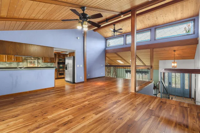 a view of an empty room with wooden floor and stairs