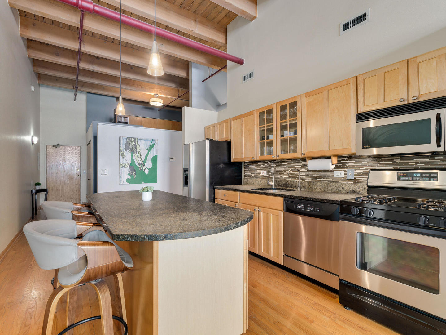 1733 West Irving Park Road, Unit 306 Chicago, IL 60613 - Photo 7 of 15 a kitchen with stainless steel appliances granite countertop a stove a sink and a microwave