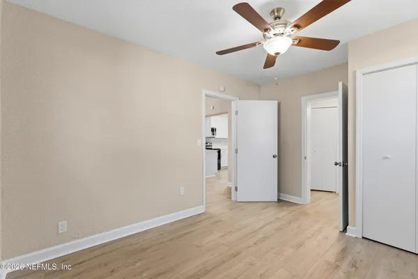 an empty room with wooden floor and a ceiling fan