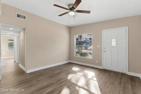 a view of an empty room with wooden floor and a window