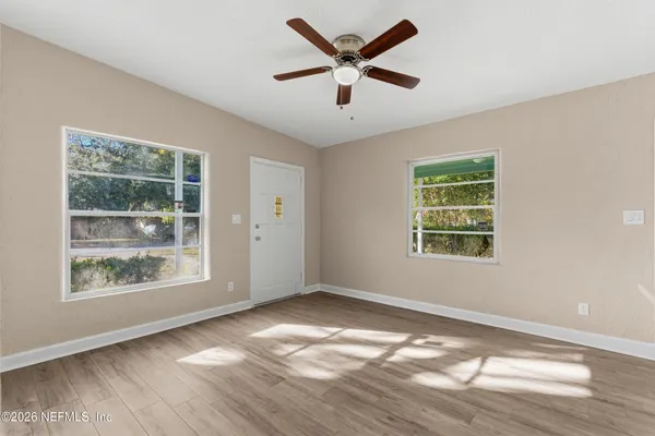 a view of an empty room with wooden floor and a window