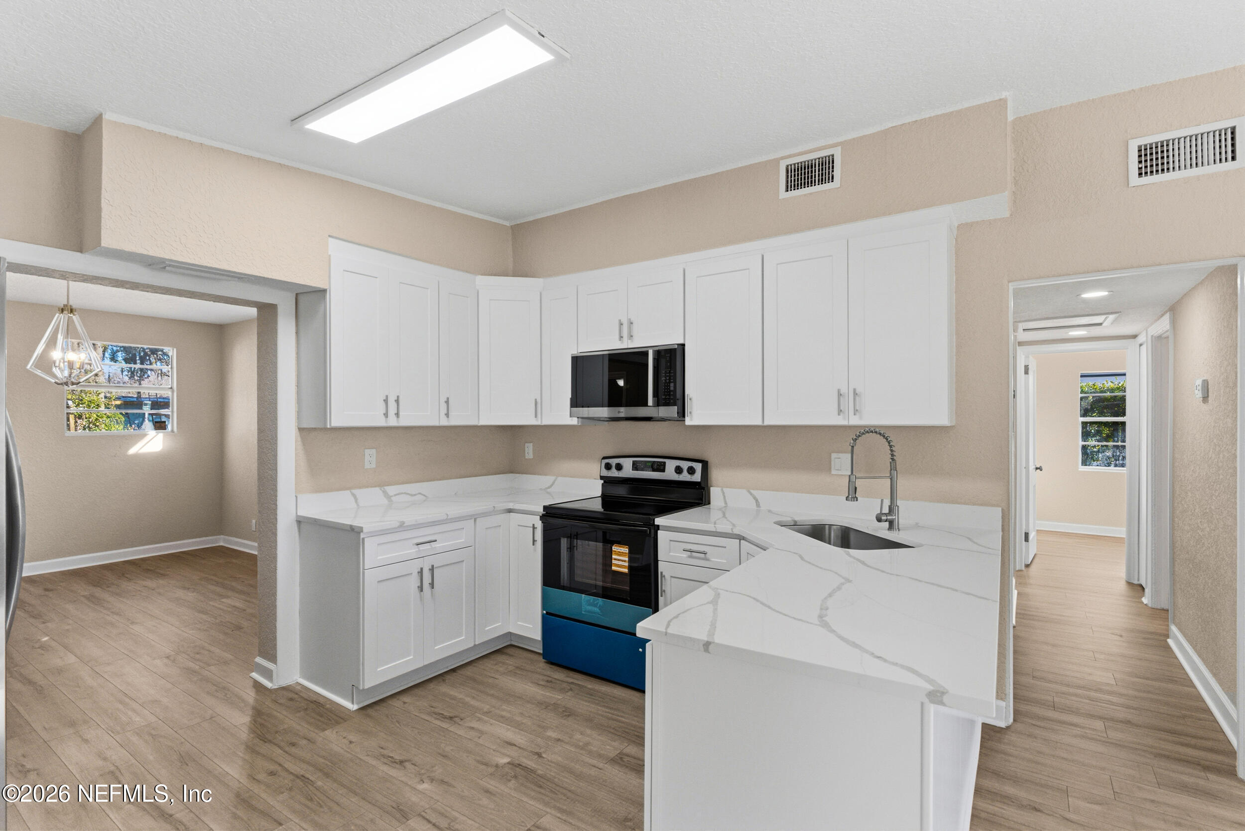 10531 Rutgers Road Jacksonville, FL 32218 - Photo 8 of 32 a kitchen with stainless steel appliances kitchen island granite countertop a sink dishwasher stove and white cabinets with wooden floor