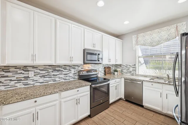 a kitchen with stainless steel appliances granite countertop a sink a stove and cabinets