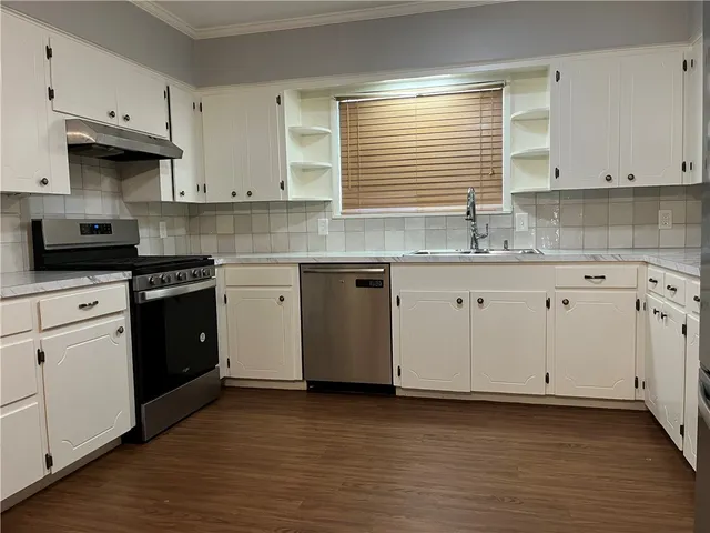 a kitchen with granite countertop white cabinets sink and stainless steel appliances