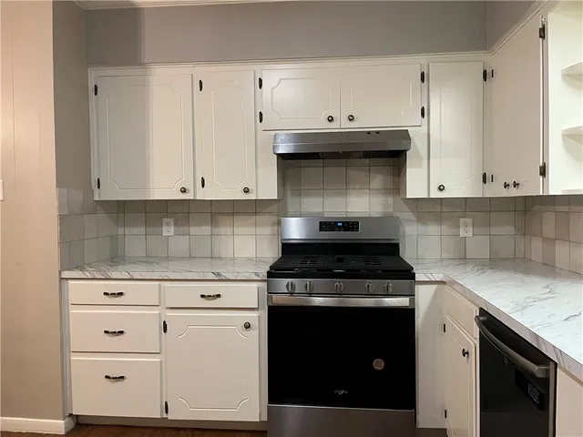 a kitchen with white cabinets and a stove with a sink