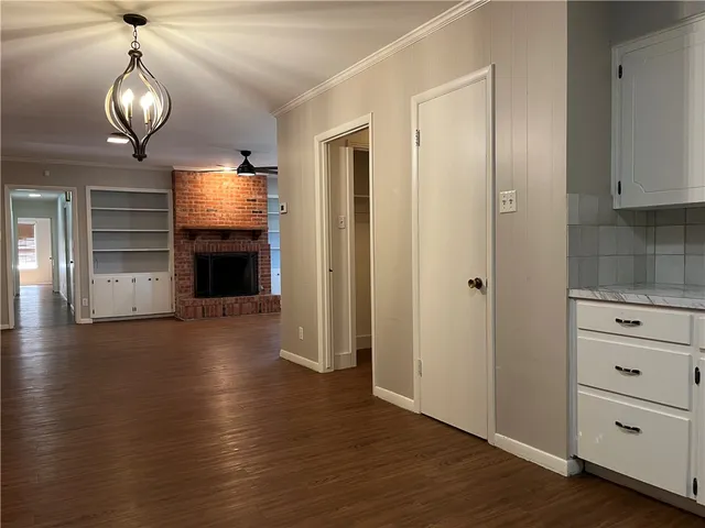 an empty room with wooden floor fireplace and staircase