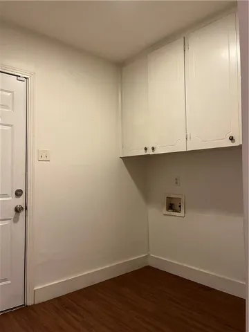 a view of an empty room with wooden floor and cabinets