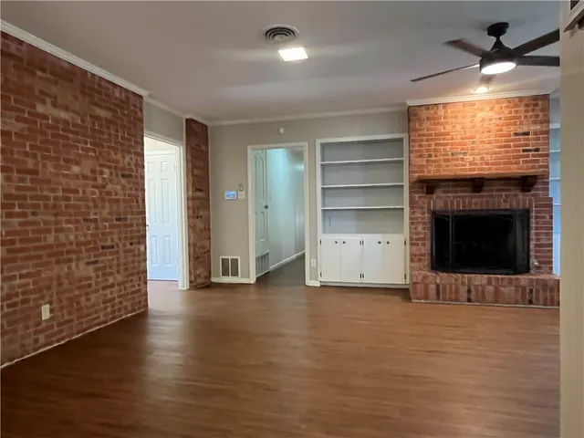 an empty room with wooden floor fireplace and windows