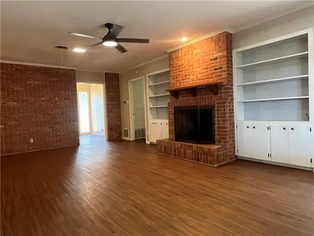a view of an empty room with wooden floor and a fireplace