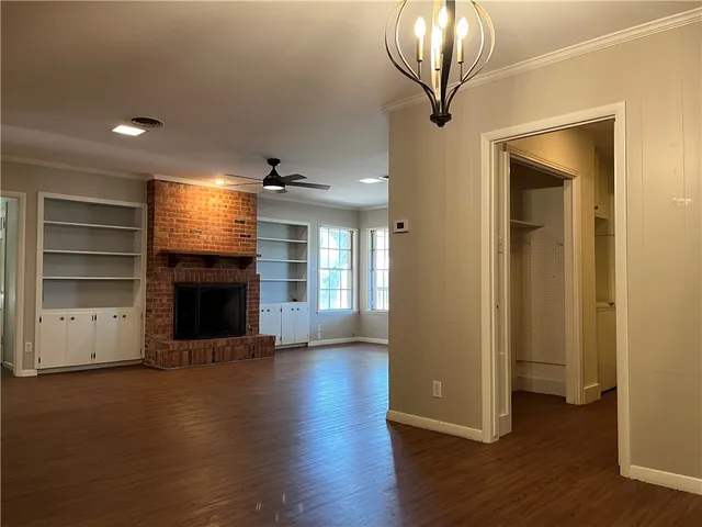 an empty room with wooden floor fire place and windows