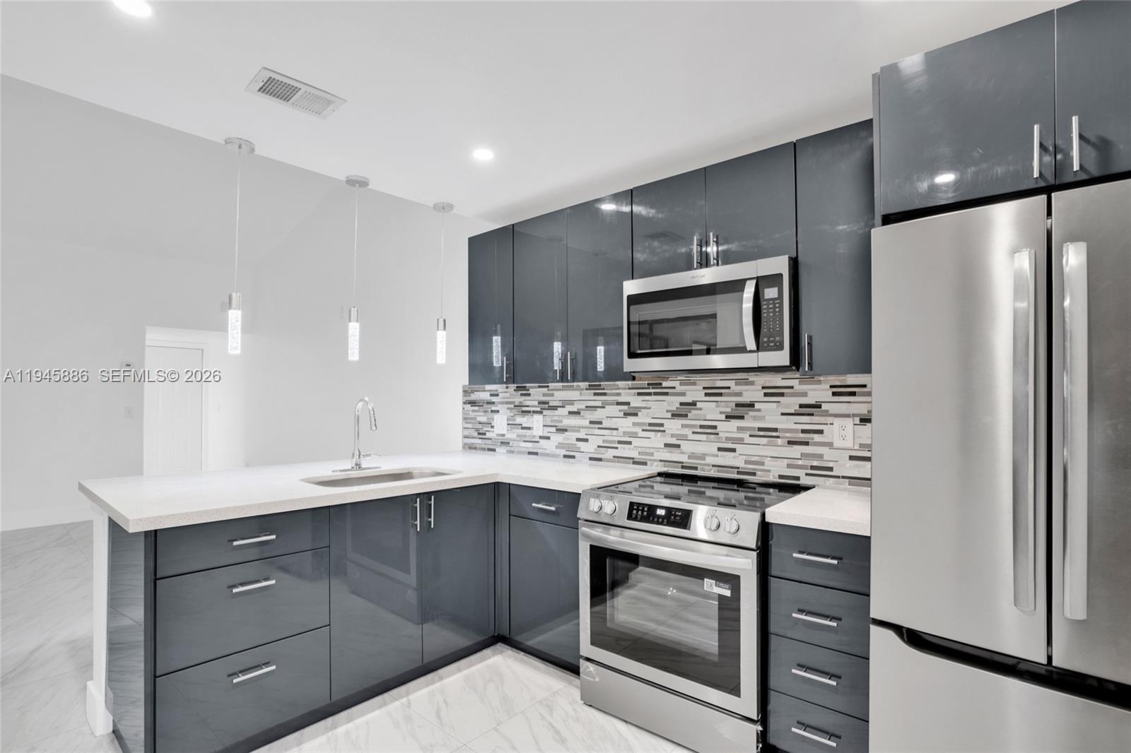1031 Adams Avenue, Unit 1031I Homestead, FL 33034 - Photo 2 of 33 a kitchen with stainless steel appliances kitchen island granite countertop a stove a refrigerator and a microwave