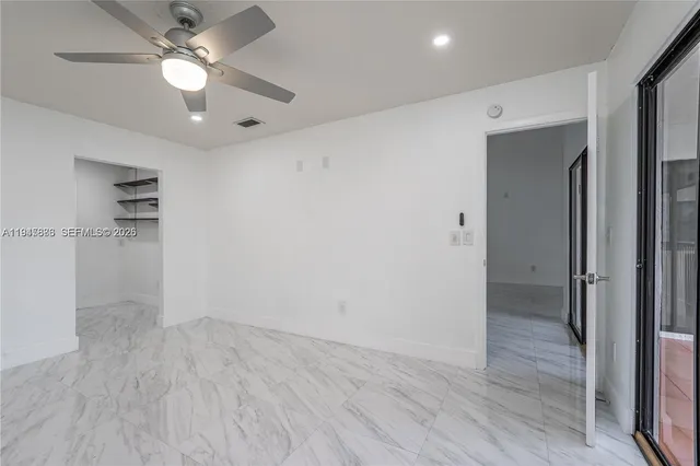 an empty room with closet and a ceiling fan