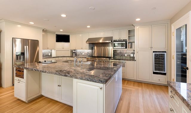 a kitchen with stainless steel appliances granite countertop a sink refrigerator and cabinets