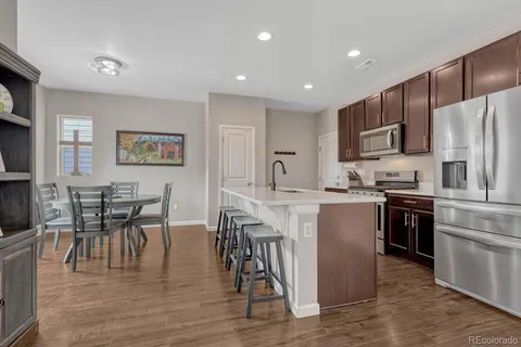 a kitchen with stainless steel appliances granite countertop a stove top oven a sink a dining table and chairs