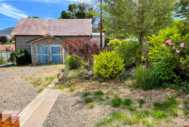 a view of a house with a small yard and large tree