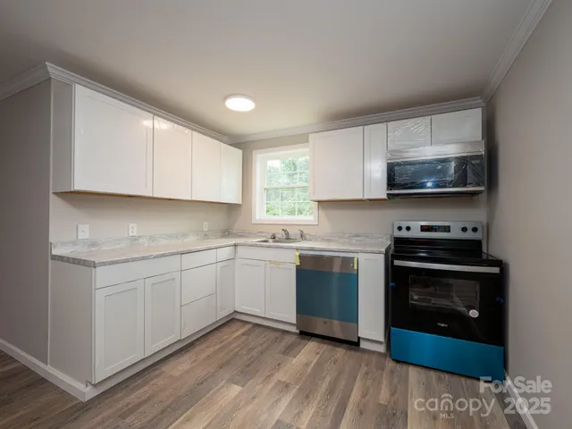 a kitchen with stainless steel appliances granite countertop a stove a sink and a microwave