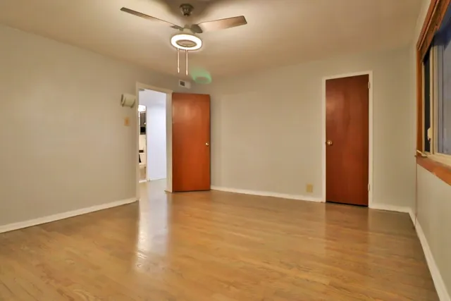 a view of an empty room with wooden floor and a window