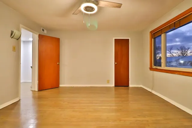 a view of an empty room with wooden floor and a bathroom