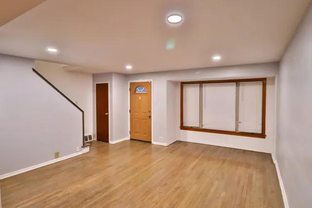 a view of an empty room with wooden floor and window