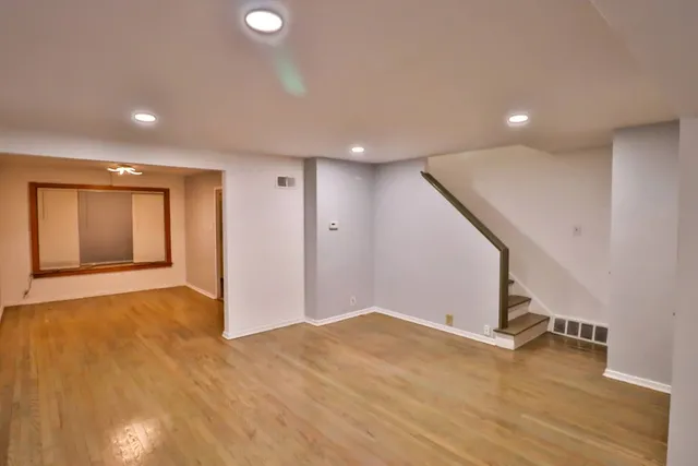 a view of an empty room with wooden floor and stairs
