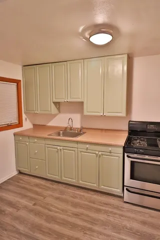 a kitchen with granite countertop a stove a sink and a dishwasher with wooden cabinets