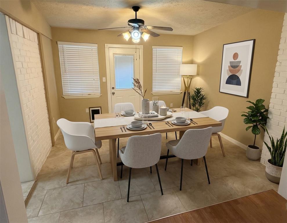 2051 Embassy Way Carrollton, TX 75006 - Photo 4 of 20 Dining room with light tile patterned floors, a textured ceiling, brick wall, and a ceiling fan