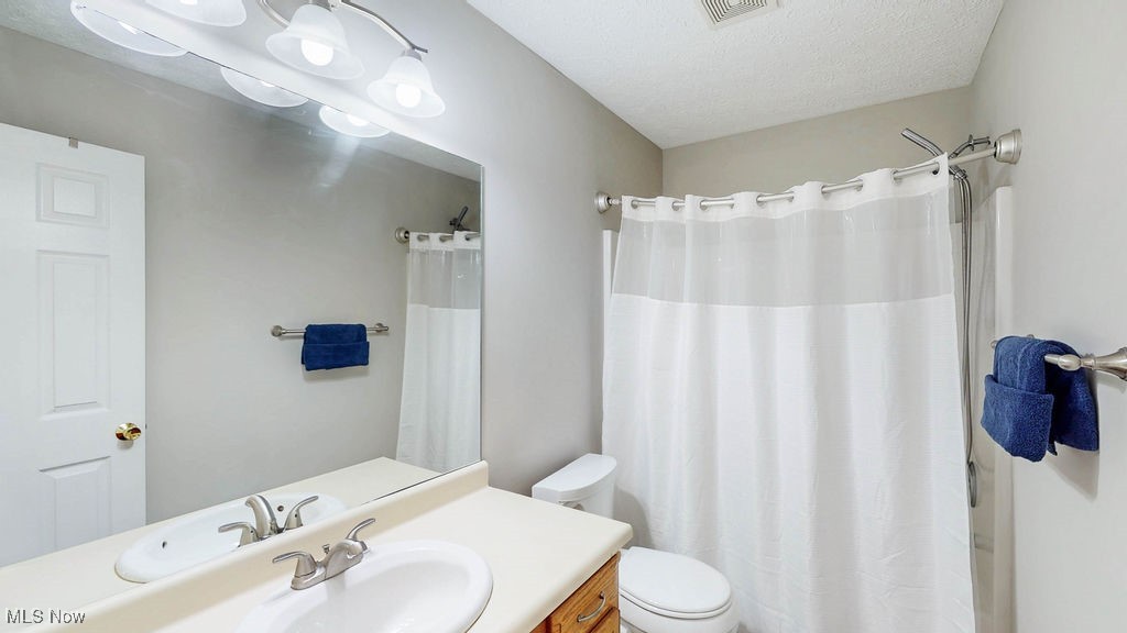 1426 Loop Road, Unit 1426 Kent, OH 44240 - Photo 18 of 40 Guest bathroom featuring vanity, a textured ceiling, and a shower with shower curtain.