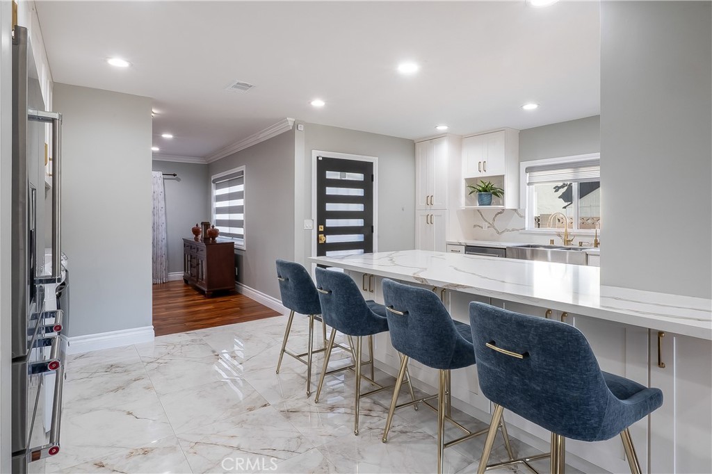 5339 East Greenmeadow Road Long Beach, CA 90808 - Photo 7 of 34 a kitchen with kitchen island a dining table chairs cabinets and stainless steel appliances