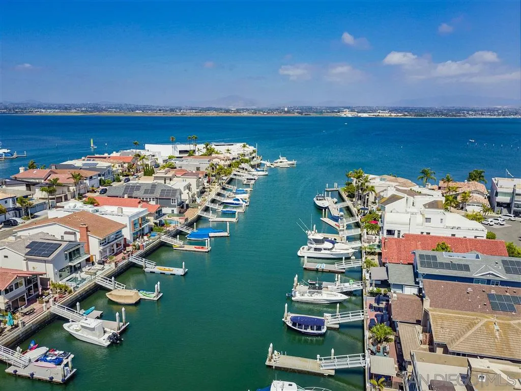an aerial view of a city with lots of residential buildings ocean and mountain view in back
