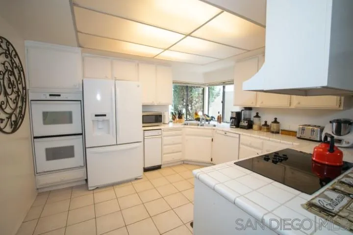 23 Sandpiper Strand Coronado, CA 92118 - Photo 7 of 25 a kitchen with white cabinets and white appliances
