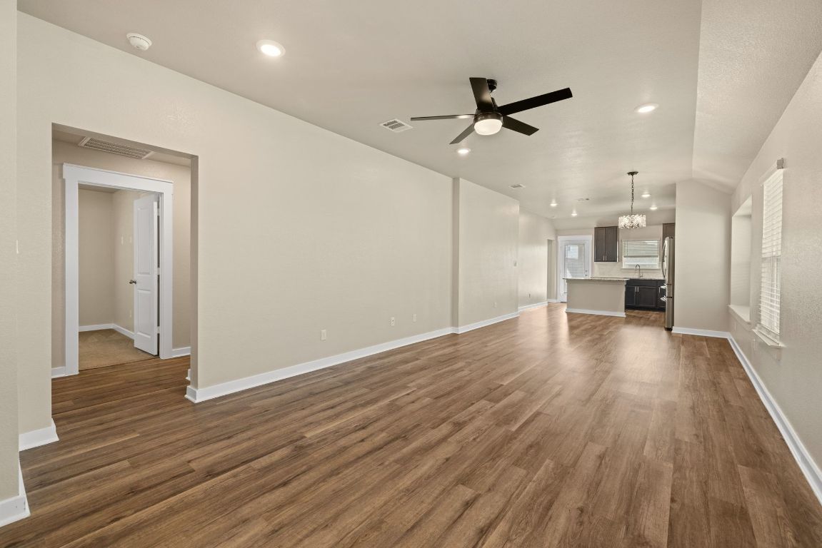 1304 Salt Lick Drive Georgetown, TX 78633 - Photo 8 of 40 an empty room with wooden floor ceiling fan and kitchen view