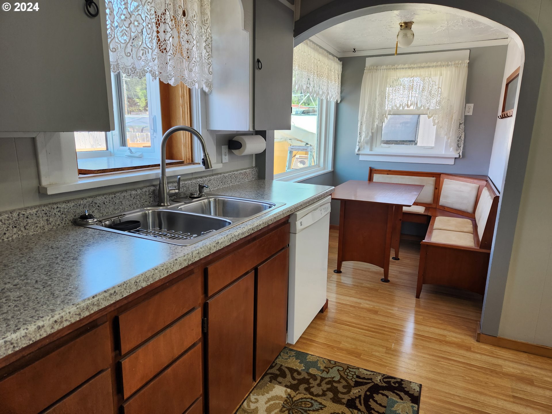 912 Fir Avenue Reedsport, OR 97467 - Photo 18 of 40 a kitchen with stainless steel appliances a sink dishwasher a stove a dining table and chair with wooden floor