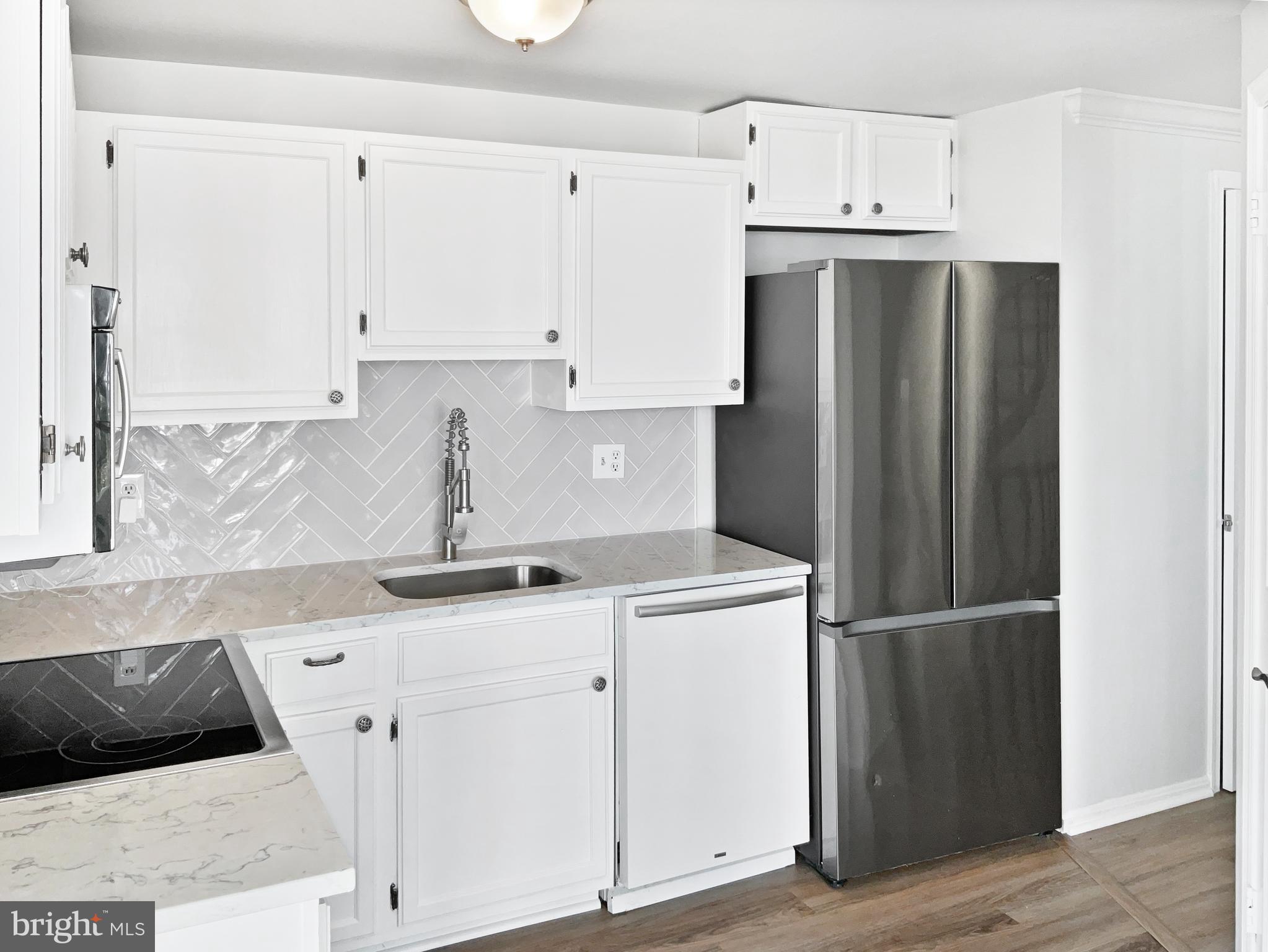 11184 Silentwood Lane Reston, VA 20191 - Photo 6 of 26 a kitchen with a sink a refrigerator and cabinets