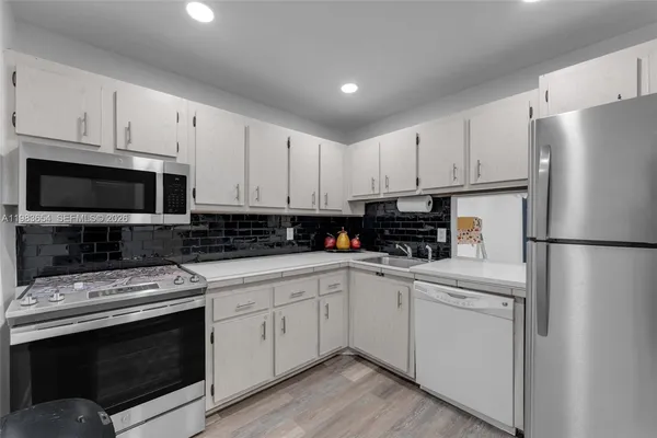 a kitchen with white cabinets and stainless steel appliances