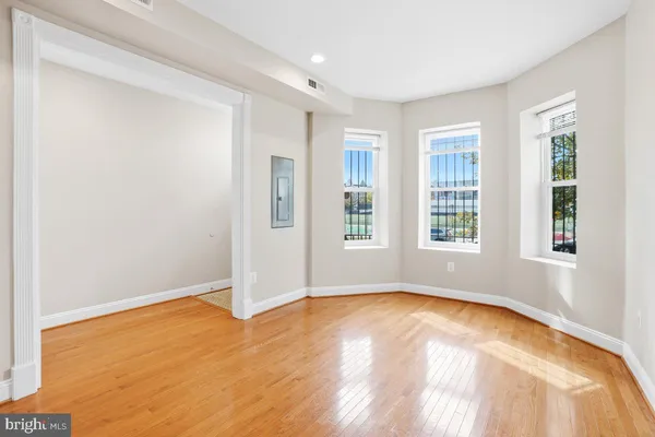 a view of empty room with wooden floor and fan