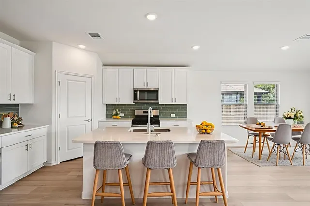 a kitchen with stainless steel appliances a dining table chairs and wooden floor