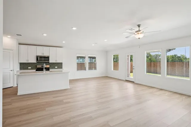 a view of an empty room with window and wooden floor