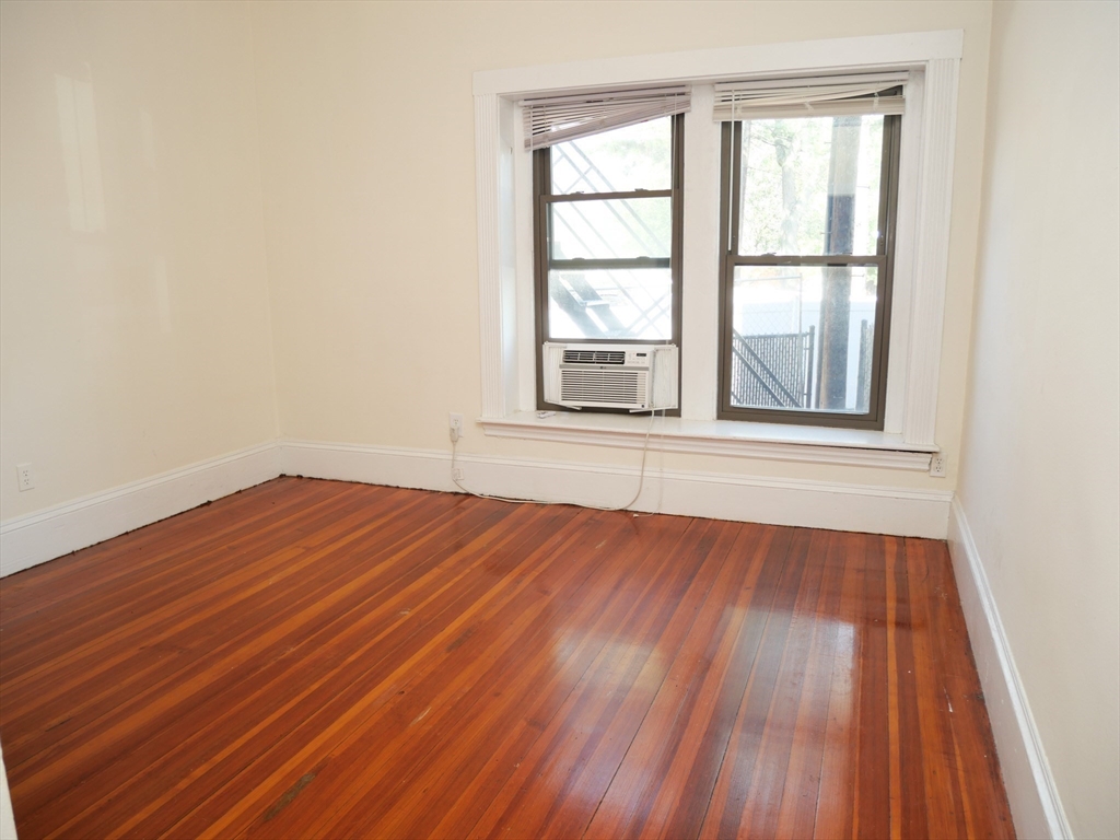 1386 Beacon Street, Unit 4 Brookline, MA 02446 - Photo 3 of 7 an empty room with wooden floor and windows