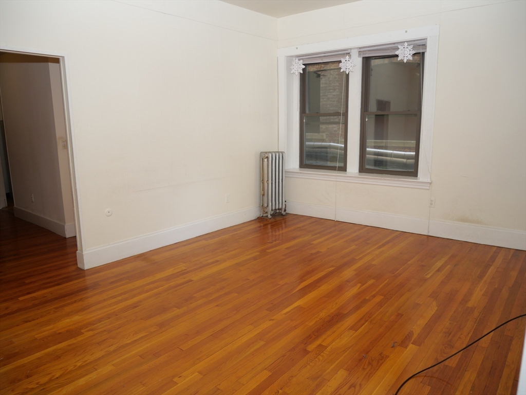 1386 Beacon Street, Unit 4 Brookline, MA 02446 - Photo 4 of 7 an empty room with wooden floor and windows
