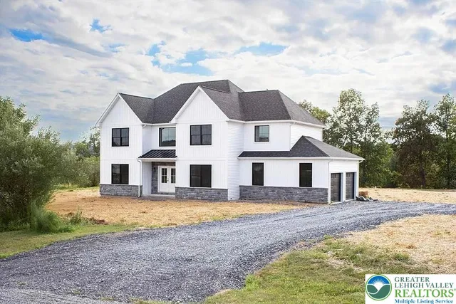 a front view of a house with a yard covered with trees