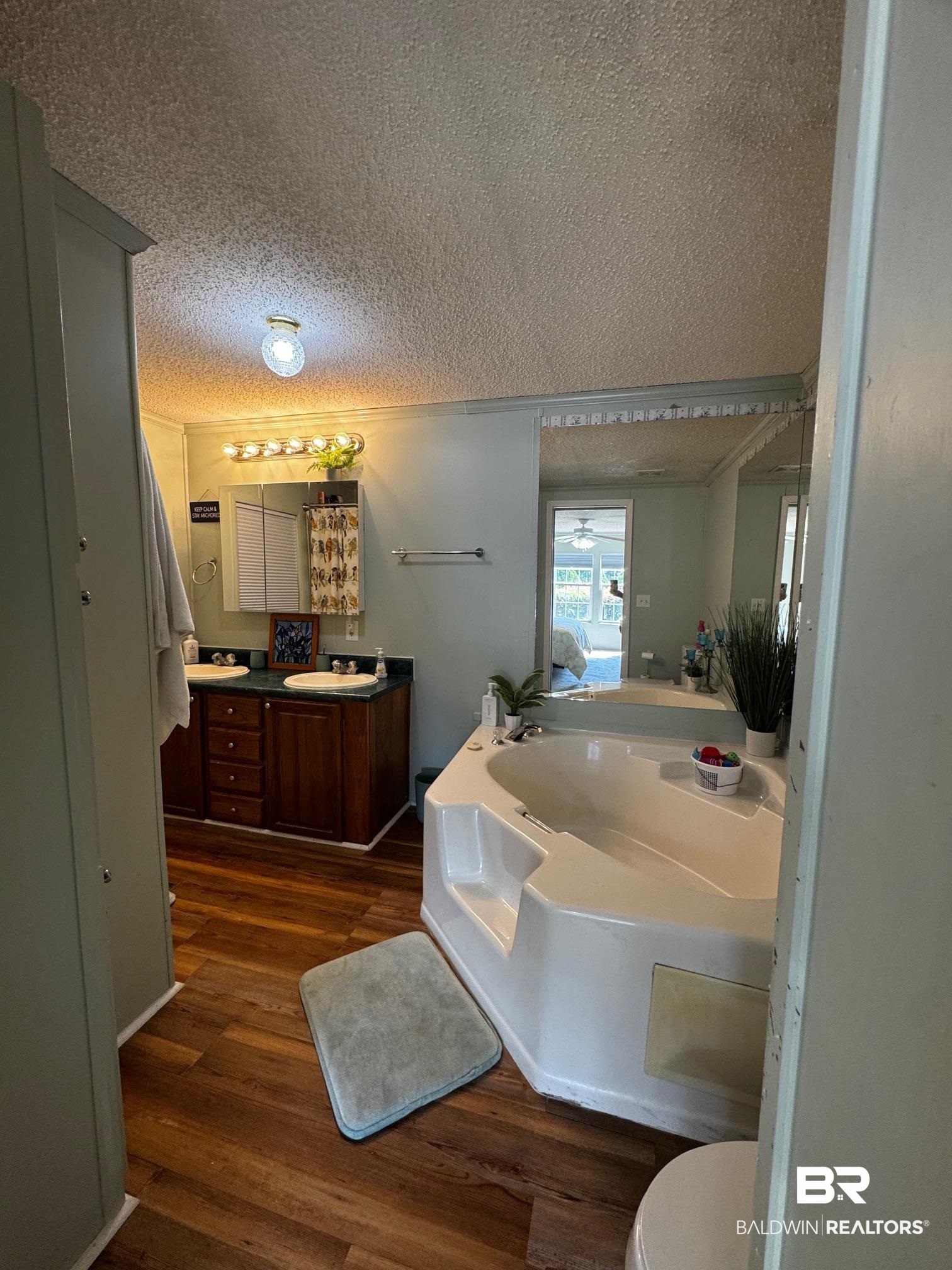1882 Cisco Circle Lillian, AL 36549 - Photo 12 of 40 Full bathroom featuring a garden tub, dark wood-style flooring, vanity, and a textured ceiling