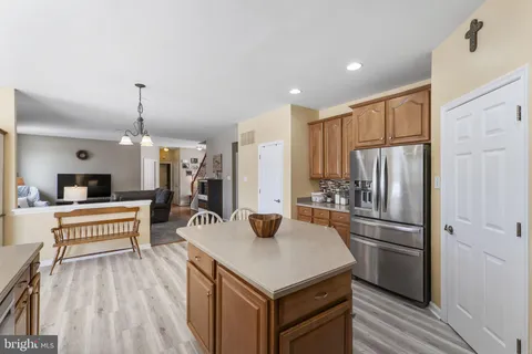 a kitchen with stainless steel appliances a refrigerator a stove a sink dishwasher and a dining table with wooden floor