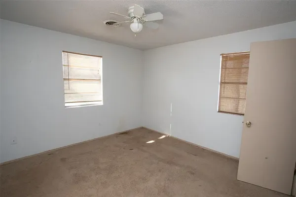an empty room with windows and fan