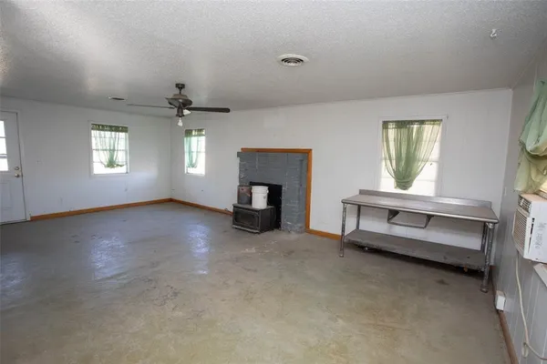 an empty room with windows and fireplace