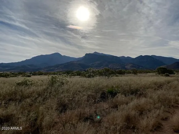 a view of a lush green field with mountains in the background