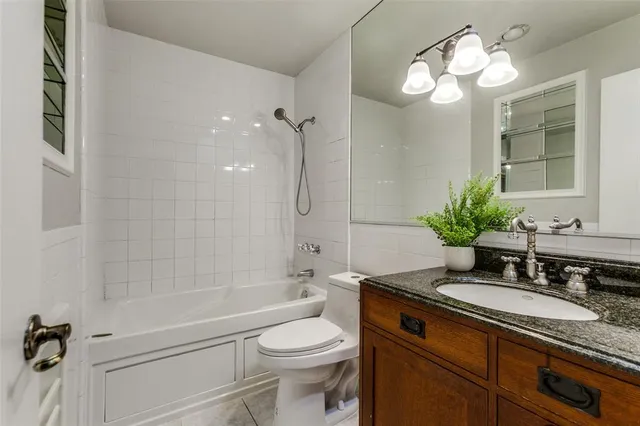 a bathroom with a granite countertop sink a toilet and shower