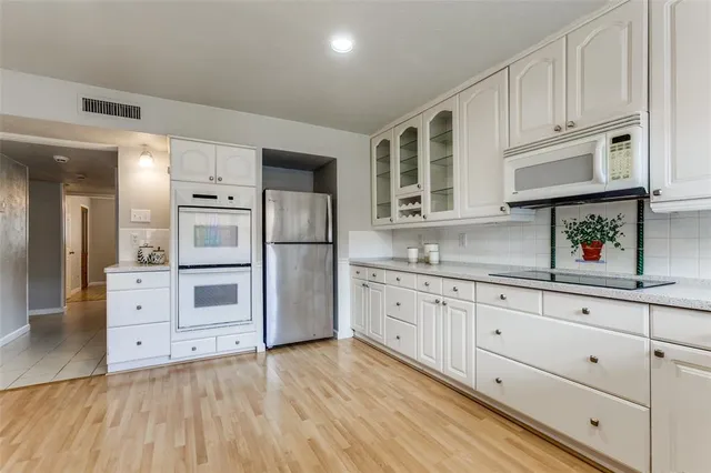 a kitchen with granite countertop white cabinets and stainless steel appliances