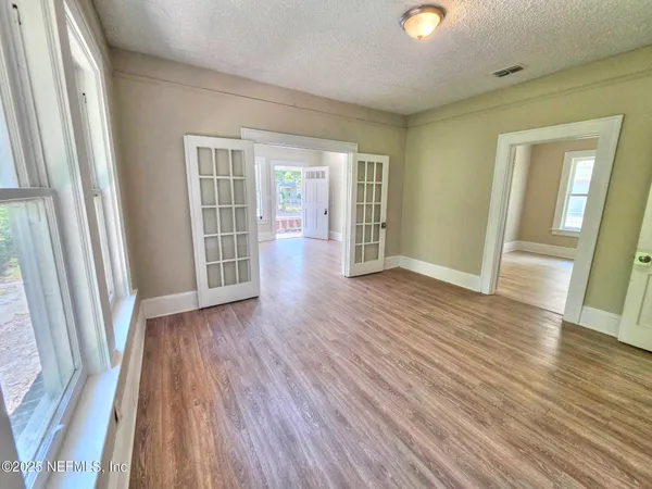 an empty room with wooden floor and windows