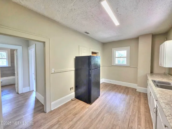 an empty room with wooden floor cabinet and windows