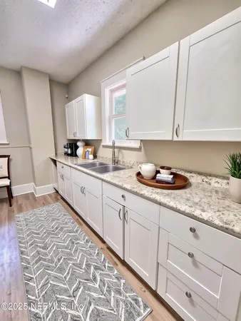 a kitchen with granite countertop a sink a stove and cabinets